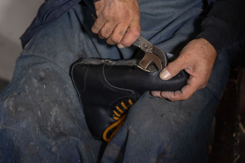 Sample photo: hands working on a black leather shoe with a tool